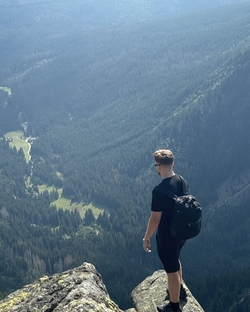 Zachary na skalnym szczycie nad zalesioną doliną